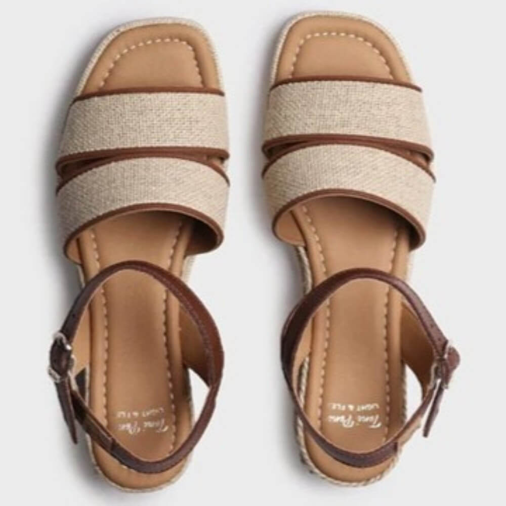 Pair of sandals with beige straps and brown accents on a light gray background