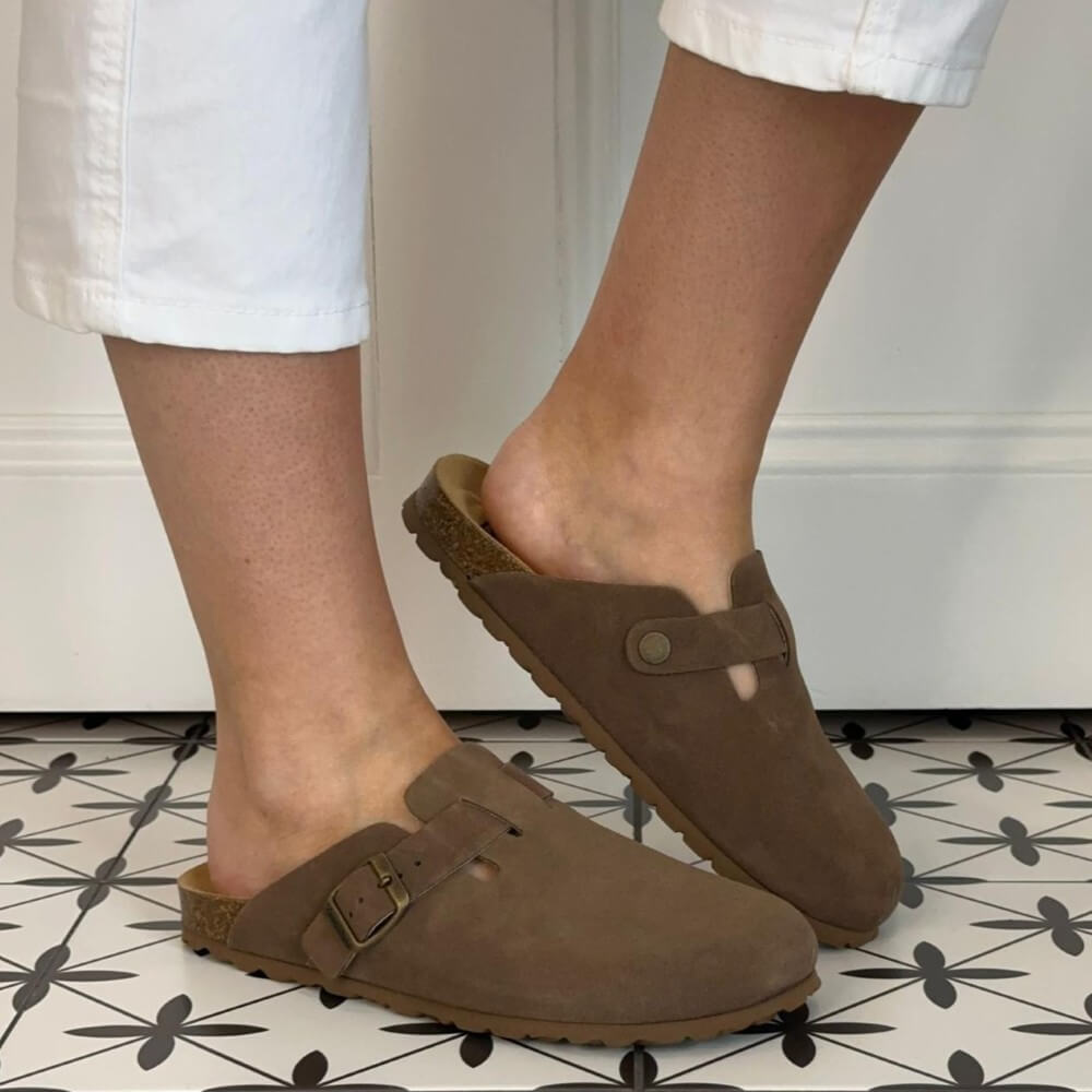 Toni Pons Brown clogs worn on feet with white pants against a neutral background