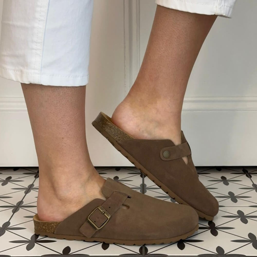 Toni Pons Brown clogs worn on feet with white pants against a neutral background