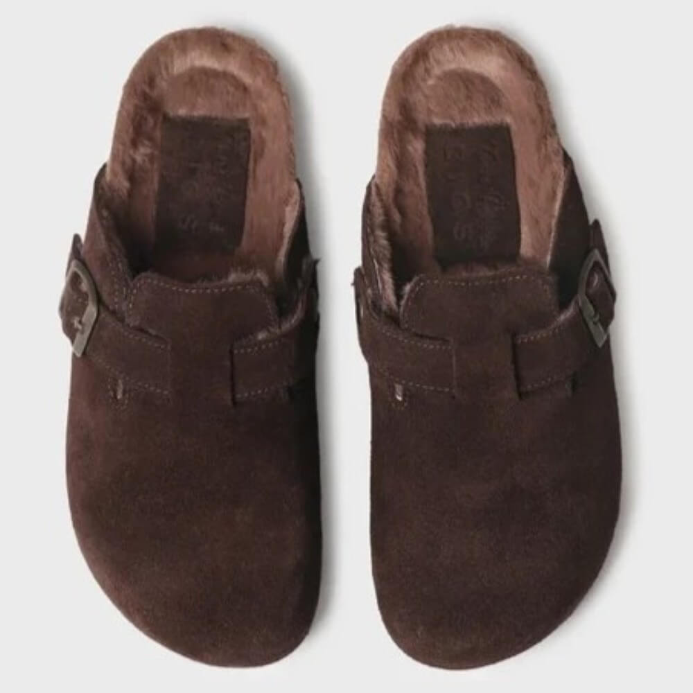 A pair of dark brown suede clogs with faux fur lining and metal buckle straps, shown from a top-down view on a light gray background.