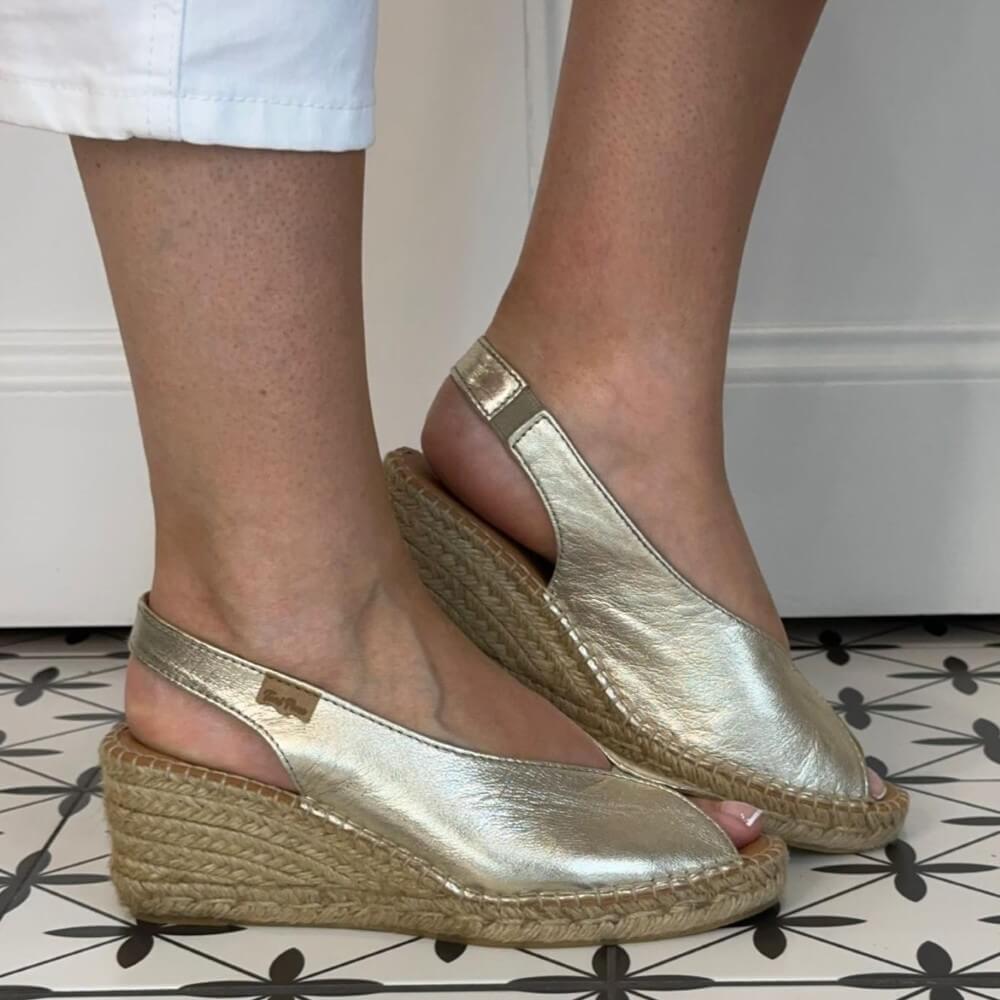 Toni Pons Gold wedge sandals worn indoors on a patterned floor.