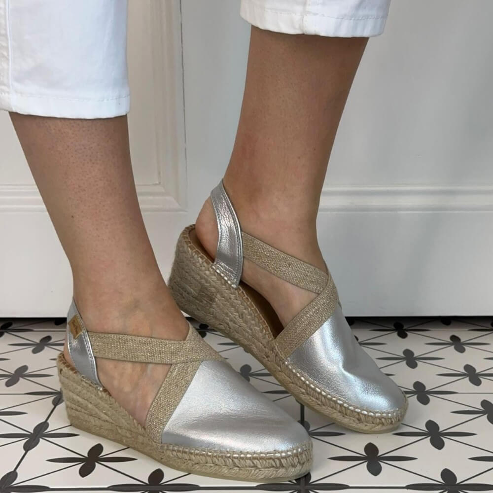 Toni Pons Silver wedge sandals with jute sole worn by a person on a patterned floor.