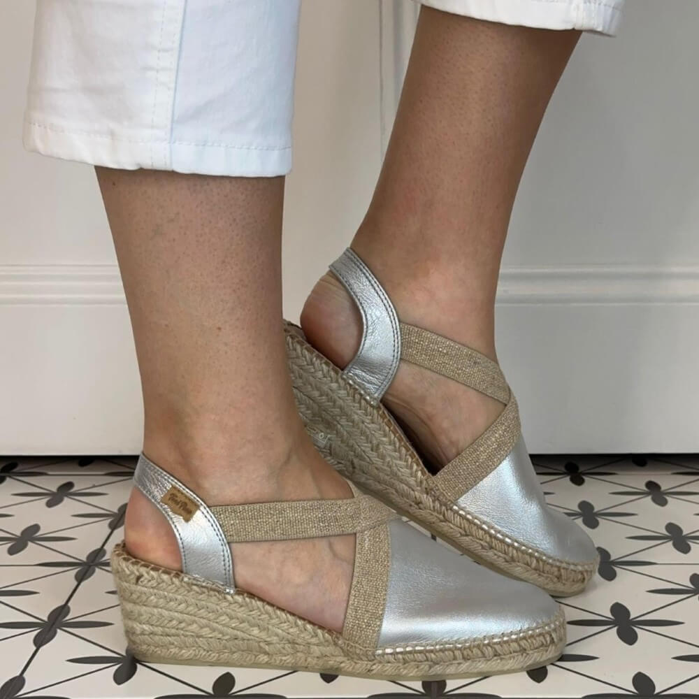 Toni Pons Silver wedge sandals with jute sole worn by a person on a patterned floor.