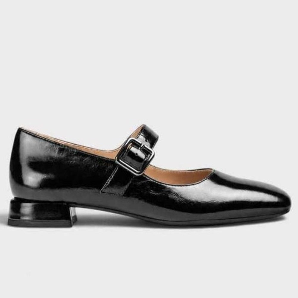A Unisa black patent leather Mary Jane flat shoe with a low block heel and a silver buckle strap, shown in profile against a light grey background.