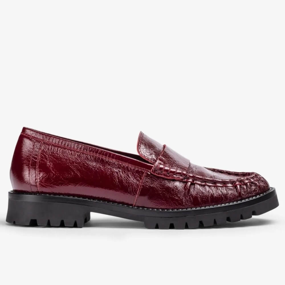 A Unisa burgundy leather penny loafer with a textured, embossed pattern and a chunky black lug sole, shown in a side profile on a light grey background.