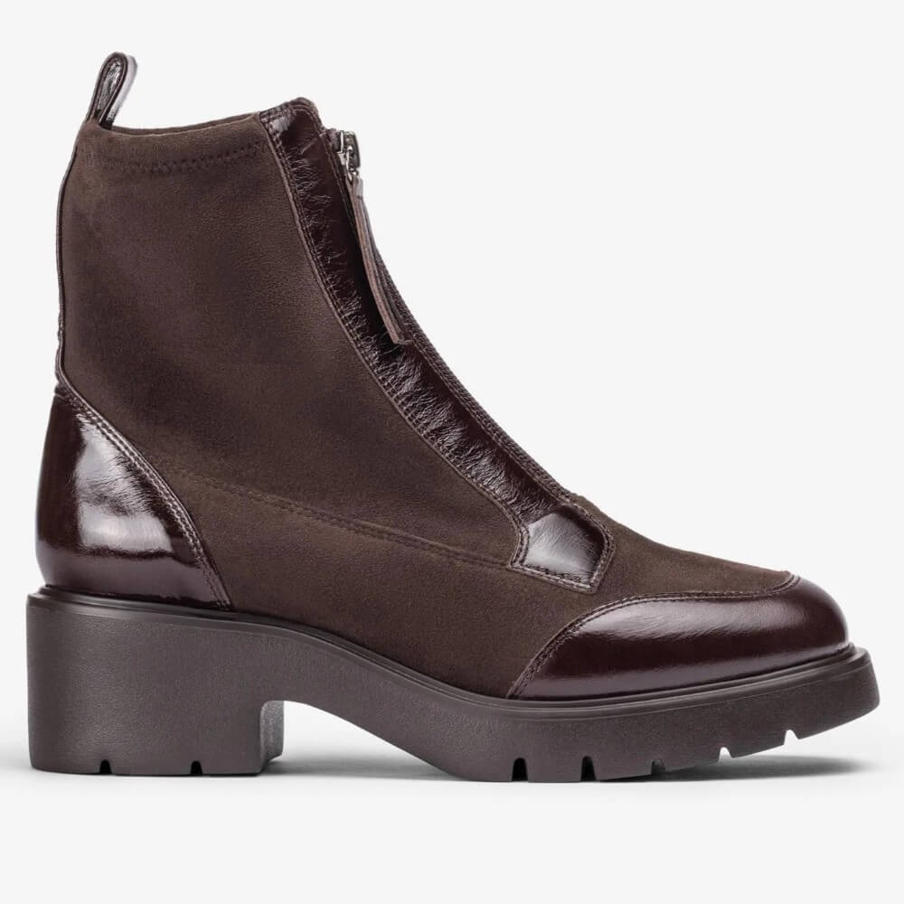 A Unisa dark brown ankle boot with a mix of matte suede and glossy patent leather panels, featuring a chunky dark sole and block heel, shown from a side profile on a light grey background.