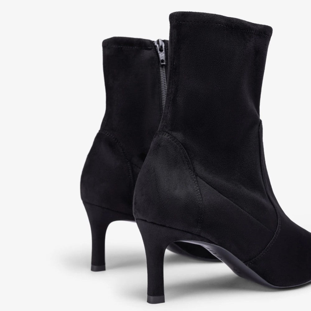 Black suede ankle boots with a pointed toe and a high stiletto heel, shown from a three-quarters rear angle on a light gray background.
