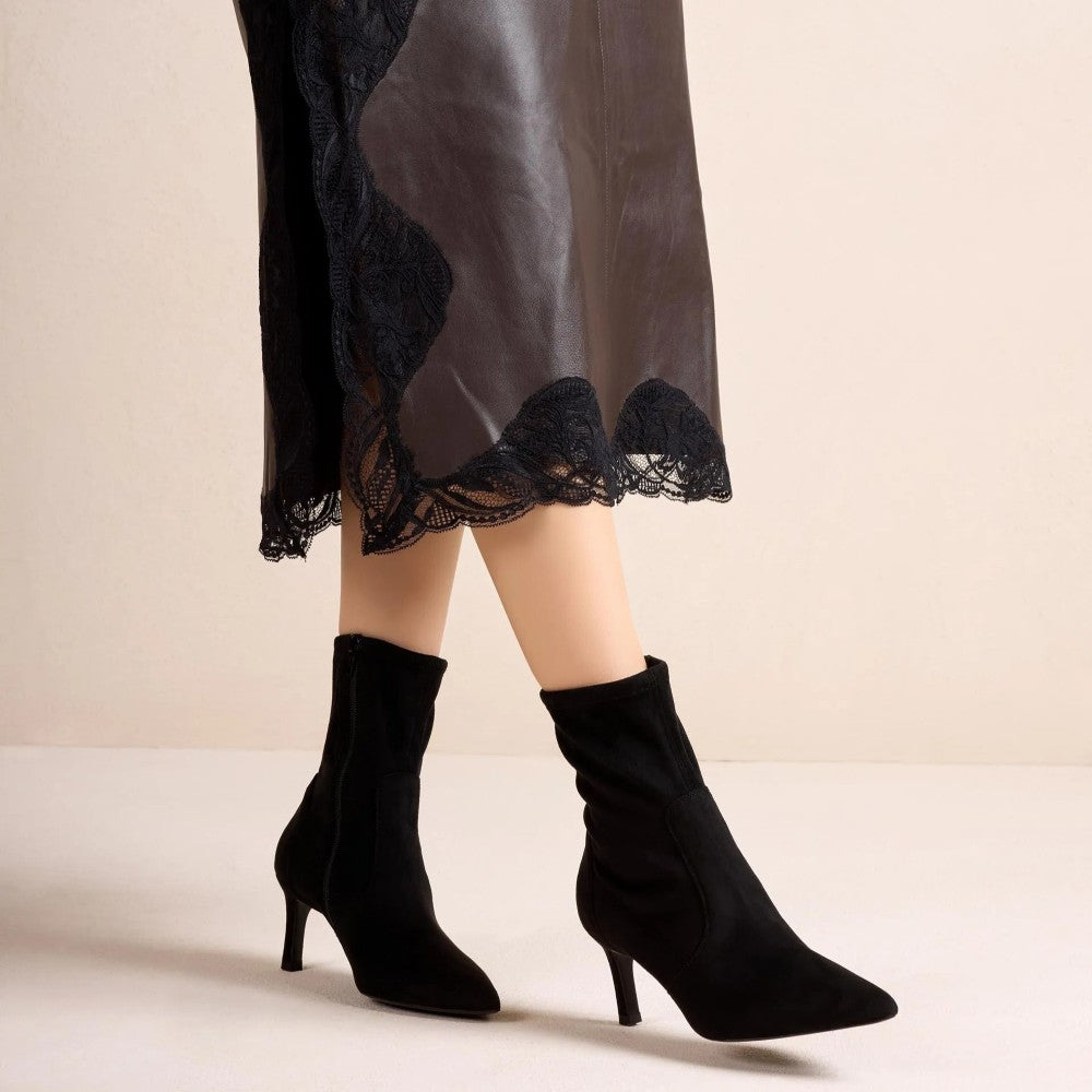 Unisa Black suede ankle boots with kitten heels, shown on a model's feet against a neutral beige background.