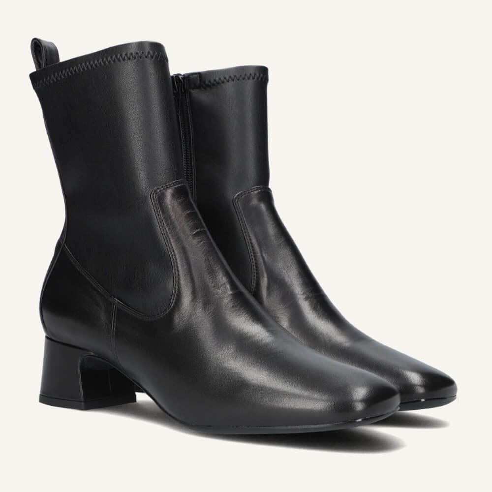 A pair of Unisa black leather ankle boots with a low block heel, square toe, and side gore detail, shown on a light off-white background.