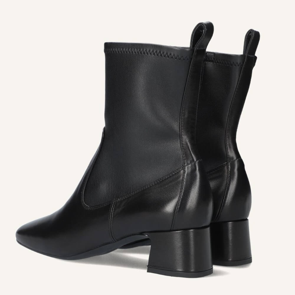 A pair of Unisa black leather ankle boots with a block heel and elastic side gore, shown from a three-quarters angle on a light off-white background.