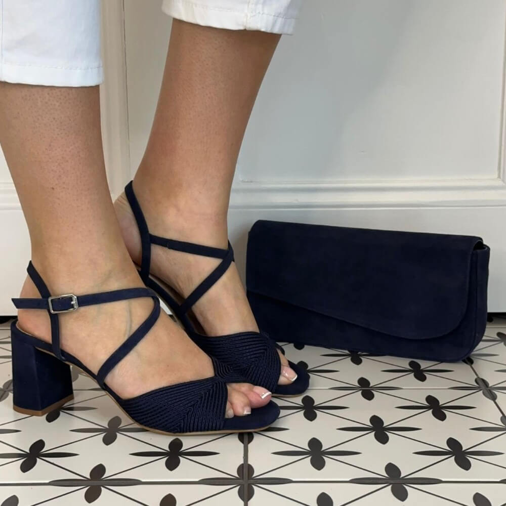 Unisa Navy sandals with a matching clutch on a patterned floor.