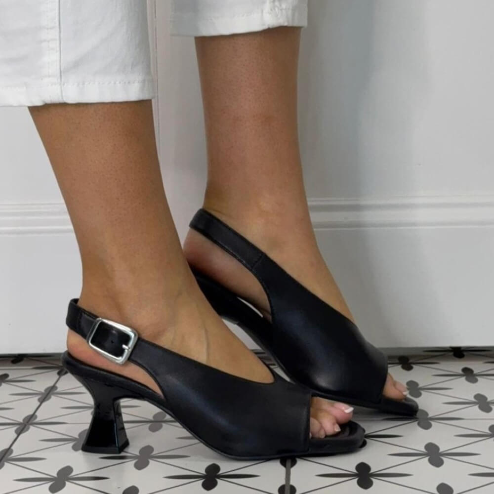 Unisa Black open-toe high-heeled shoes worn by a person on a patterned floor.