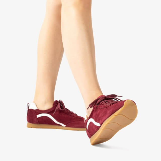 Maroon red sneakers with white accents worn by a person on a light background Unisa Dalai Suede Trainer Wine