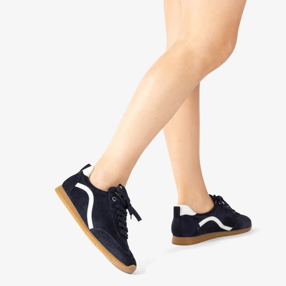 Navy sneakers with white accents worn by a person on a light grey  Unisa Dalai Suede Trainer Navy