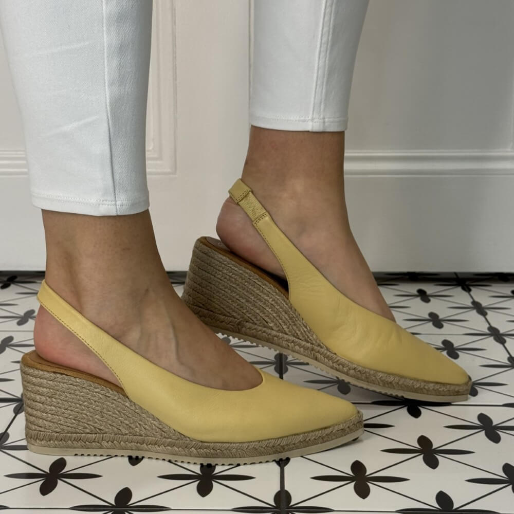 unisa decia Yellow wedge sandals with jute sole worn indoors on a patterned floor.