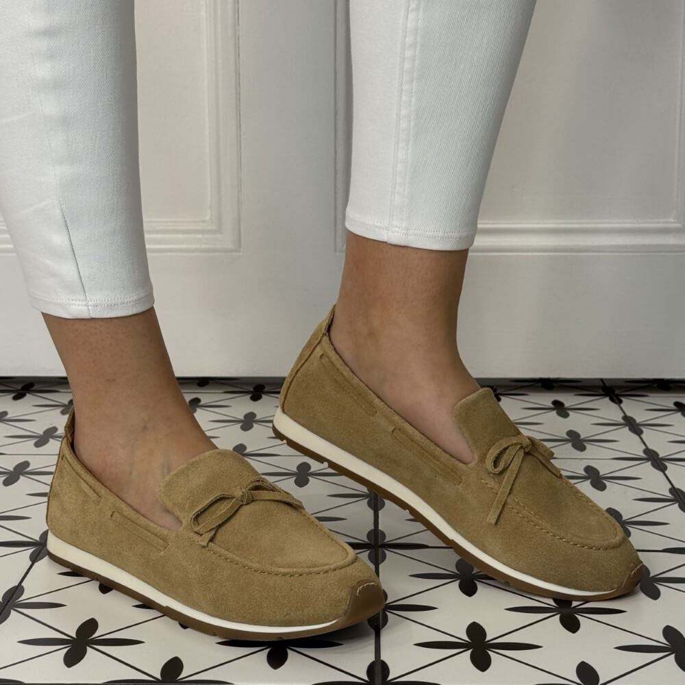 Unisa Dimas Brown loafers worn with white pants on a patterned floor.