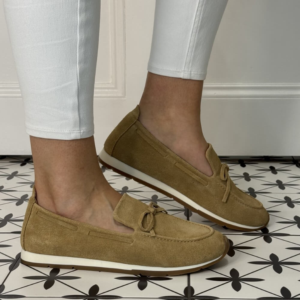 Unisa Dimas Brown loafers worn with white pants on a patterned floor.