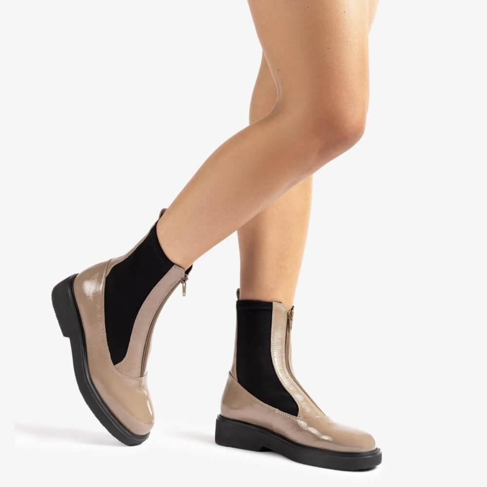 Beige and black Chelsea boots worn by a person on a white background Unisa Foggia Centre Zip Patent Leather Boot Taupe