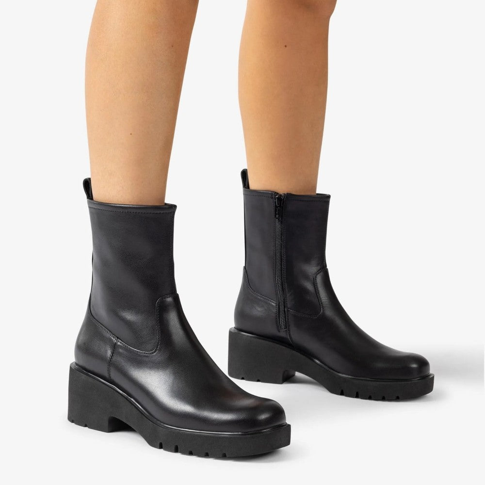 Black leather boots worn by a person on a white background