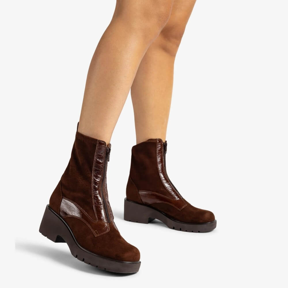 Brown ankle boots worn with beige tights on a white background Unisa Jogin Round Toe Ankle Boot Bombon Brown