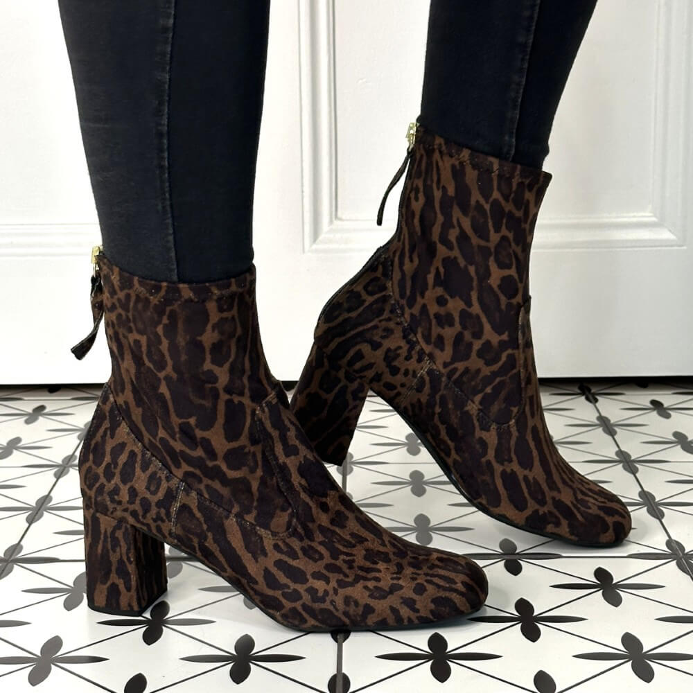 pair of leopard print sock boots with a back zip worn with black jeans an a patterned floor