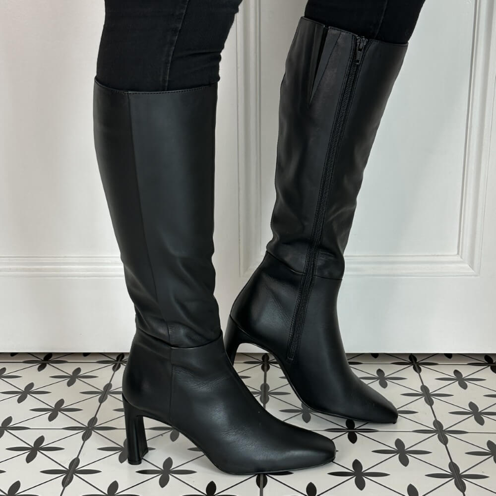 Black knee-high boots on a patterned floor with a white wall background Unisa Wolcot Leather Knee High Boot Black