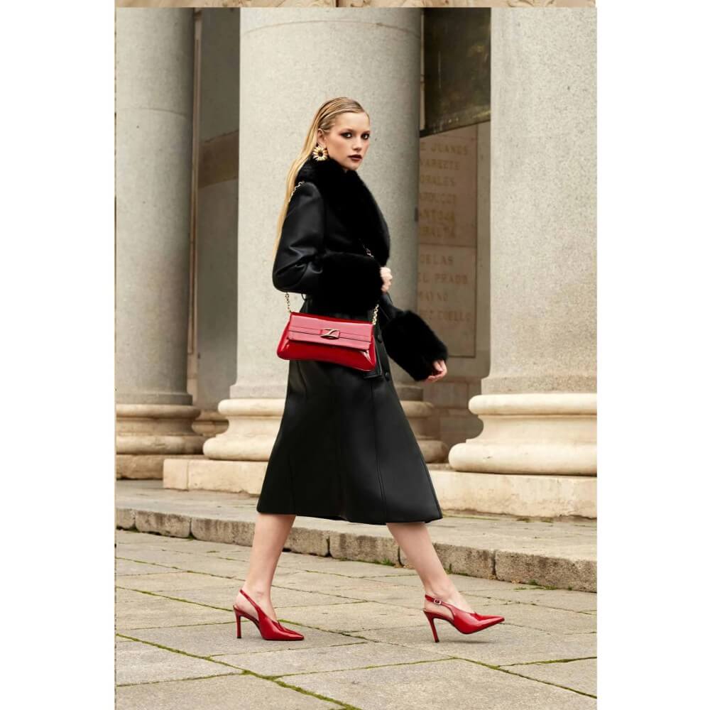 Woman in black outfit with red handbag and shoes standing in front of classical columns. Unisa ZBlair Raspberry Red Patent Shoulder Bag