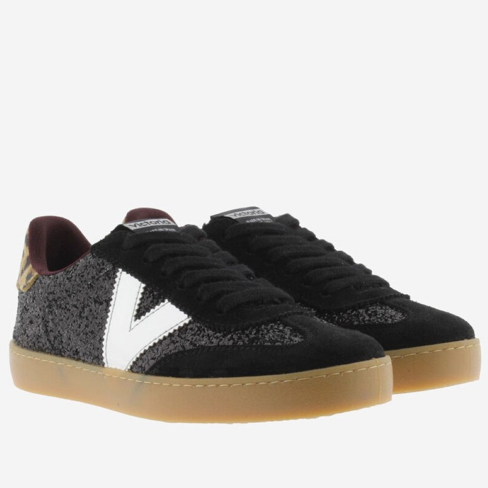 A pair of Victoria low-top sneakers in black suede and textured black mesh, featuring a prominent white V logo on the side, a burgundy inner lining, and a translucent gum sole.
