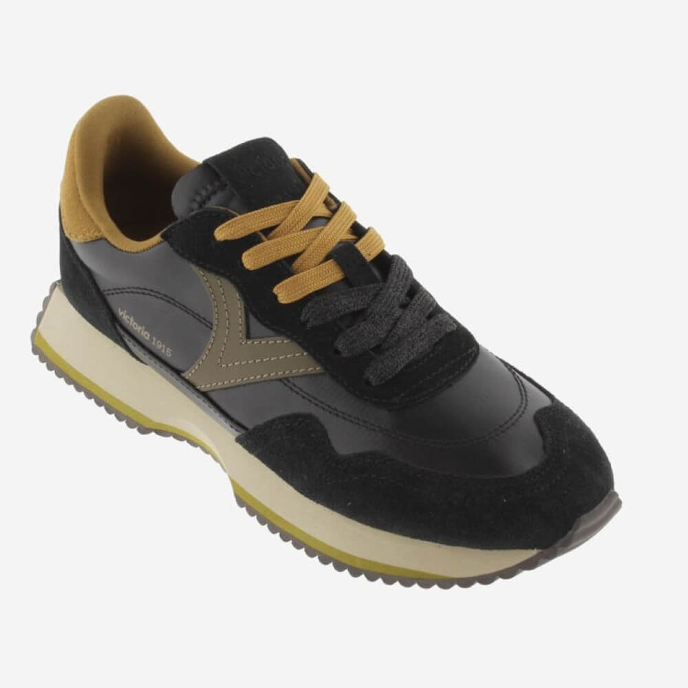 A Victoria low-top sneaker in black and suede with tan accents, featuring a thick cream midsole and a tan outsole edge, shown on a light grey background.