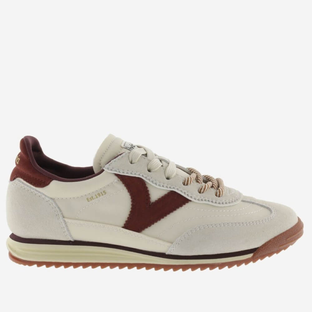 A Victoria low-top sneaker in off-white suede and leather with a prominent dark burgundy V-shaped side stripe, burgundy heel tab, and a brown textured outsole, shown against a plain light grey background.