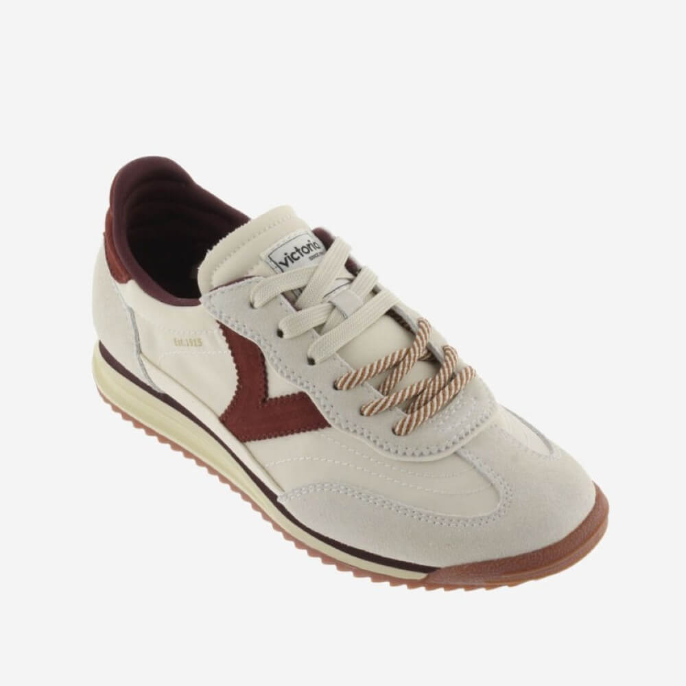 A low-top sneaker by Victoria, featuring an off-white suede upper with a dark burgundy V-shaped accent on the side, matching burgundy laces, and a brown gum sole.