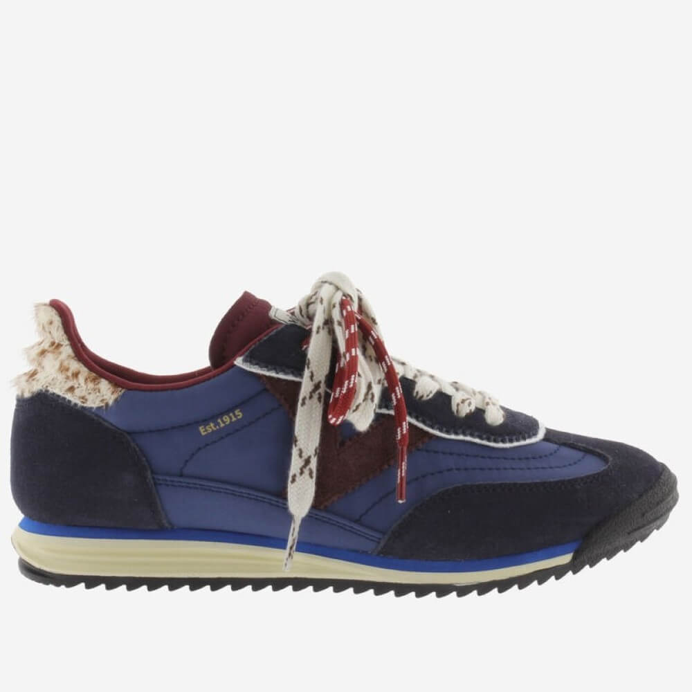 A low-top sneaker by Victoria featuring navy blue suede and synthetic panels, burgundy accents, cream-colored patterned laces, a cream midsole, and a black outsole, shown from a side profile on a light grey background.