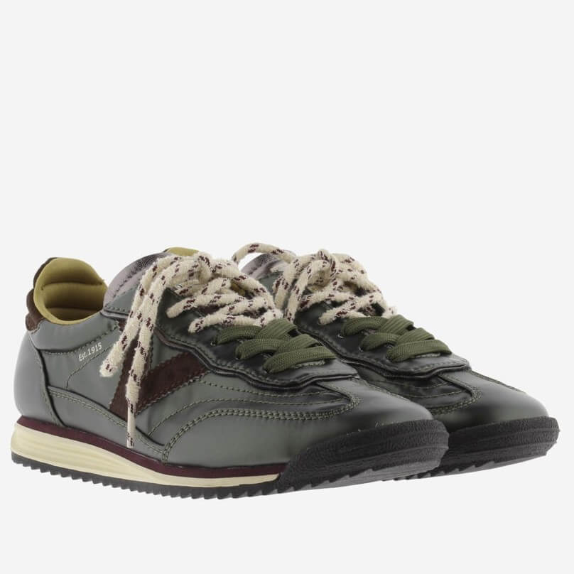 A Victoria low-top sneaker in dark olive green and brown with cream-colored laces and a cream midsole, shown from a side profile on a light grey background.