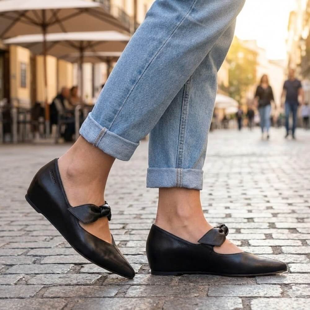 Wonders A-3840 Person wearing black shoes with a bow and rolled-up jeans on a street.