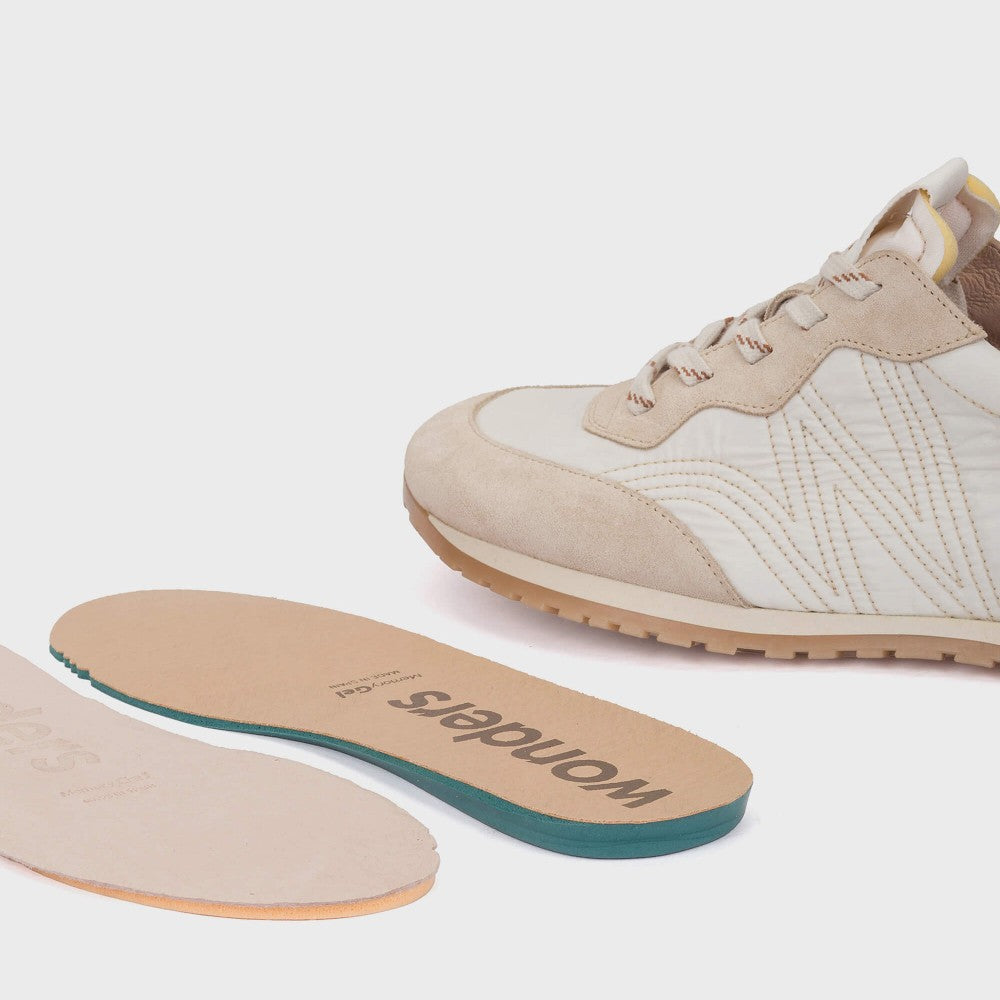Beige sneaker with a visible insole on a white background