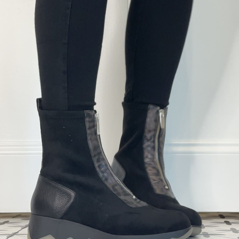 Wonders Black ankle boots with front zippers and textured side panels, worn with black leggings against a white wall.