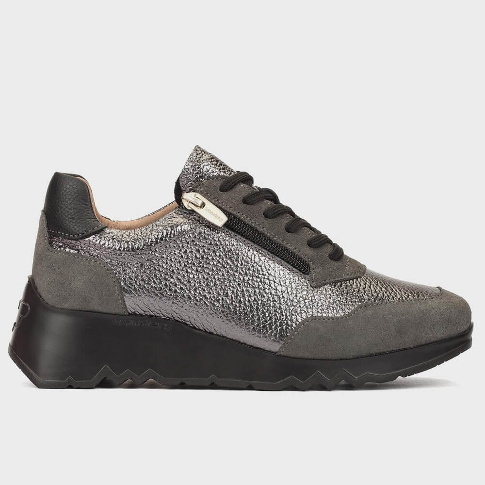 A Wonders women's low-top sneaker shown in profile against a light gray background. The shoe features a textured metallic silver upper with dark grey suede panels, black laces, a black heel counter, and a chunky black sole with a wavy tread pattern.