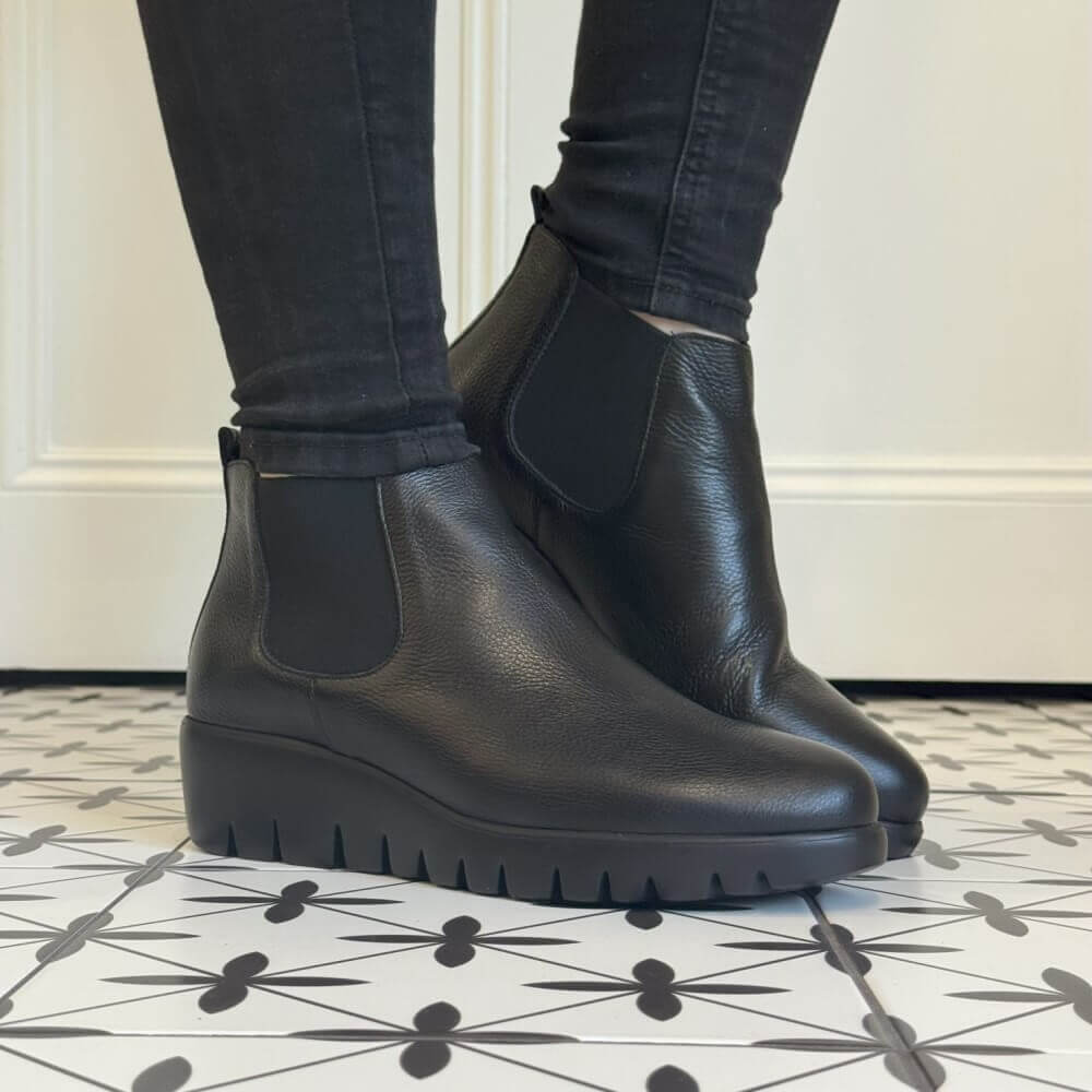 Black Chelsea boots worn with black pants on a patterned floor. Wonders Leather Chelsea Boot C-33138 WONDERS-BLACK