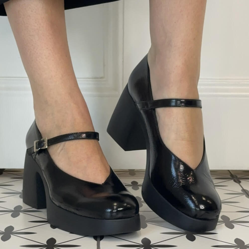 A pair of Wonders black patent leather Mary Jane platform heels with chunky block heels and ankle straps, shown on a person's feet.