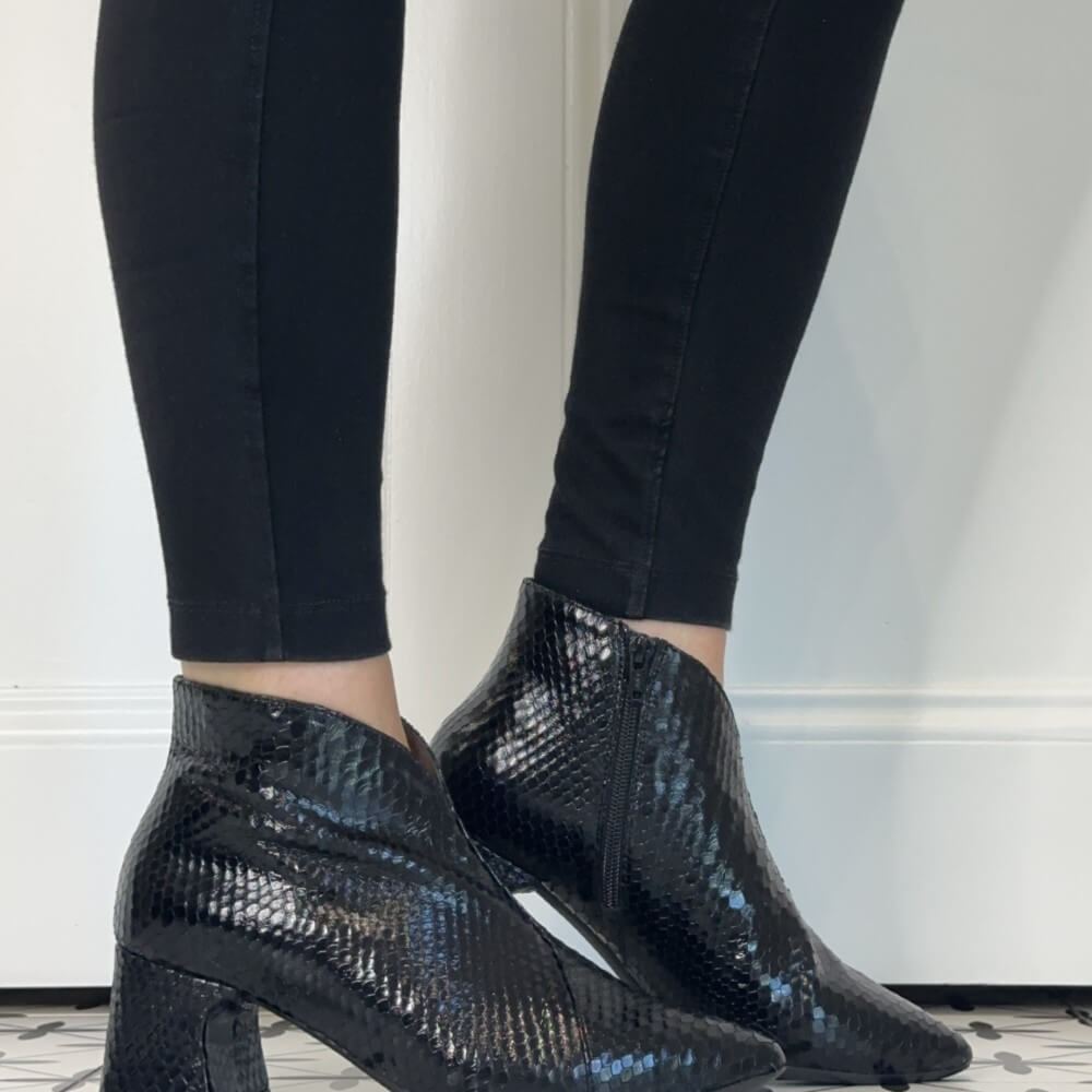 Wonders Black snakeskin ankle boots with a block heel, shown on a model wearing black skinny pants.