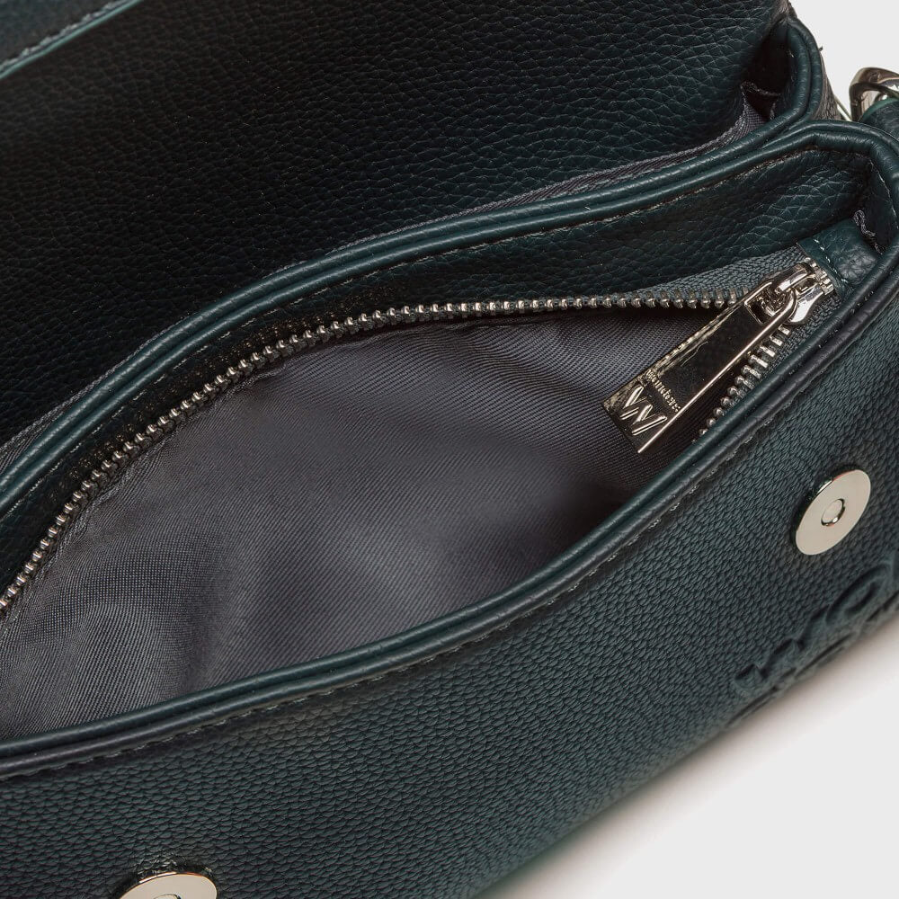 Close-up of a dark teal pebbled leather handbag showing the interior zippered compartment with a silver zipper pull and metal snap button.