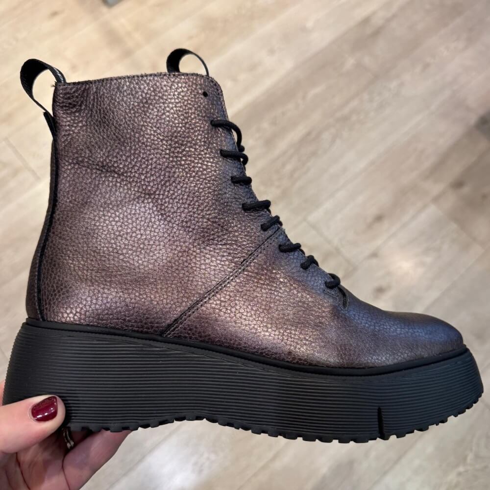 Bronze leather boot with a thick sole held by a hand on a wooden floor. Wonders Sage 50 Laced Leather Boot A-9350-Plomo