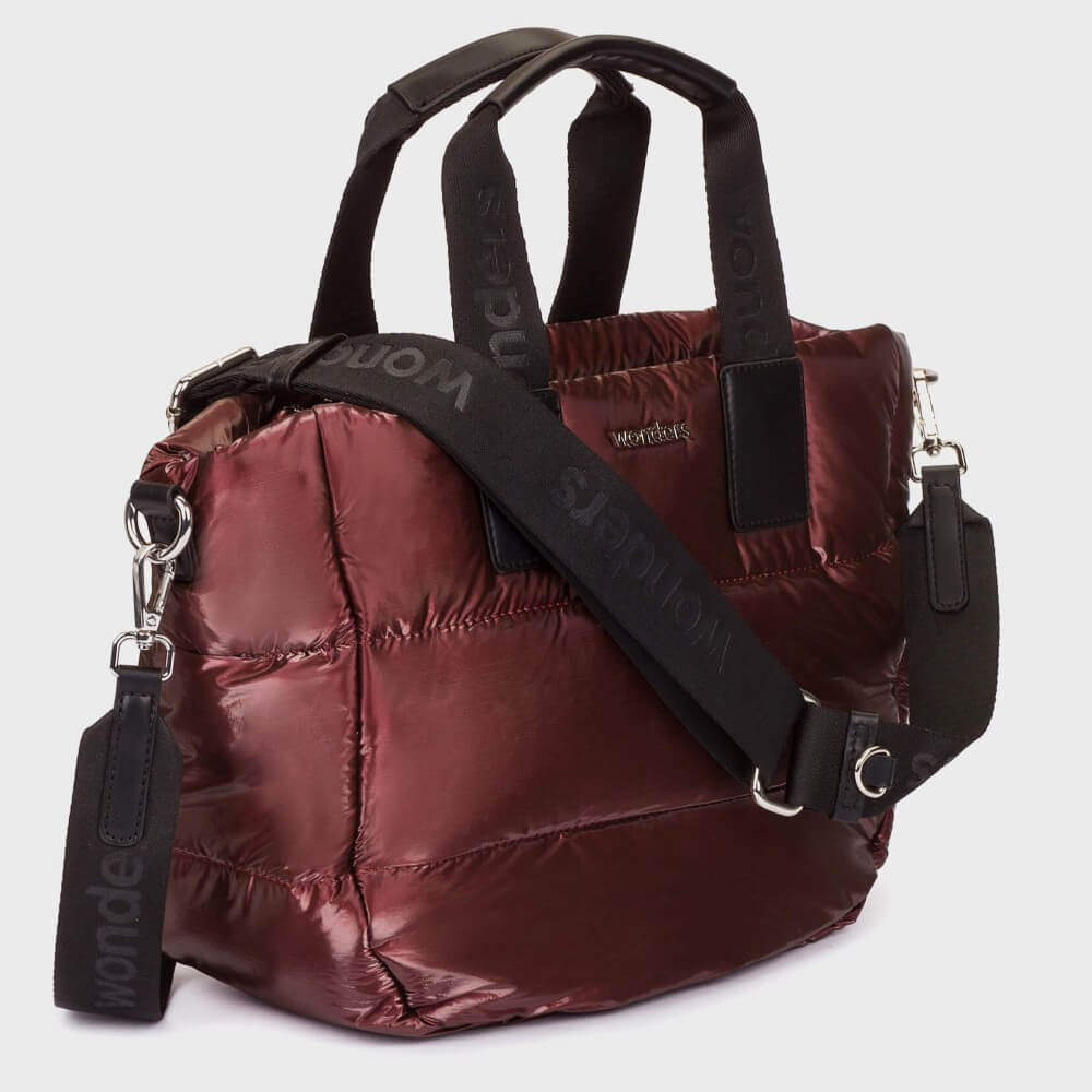 A Wonders shiny burgundy puffer duffel bag with black handles and a black shoulder strap featuring the brand name 'WONDERS' in dark lettering, set against a light grey background.