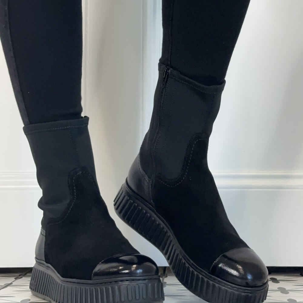 Wonders Black mid-calf boots with a glossy patent leather toe cap and chunky lug sole, worn with black leggings.