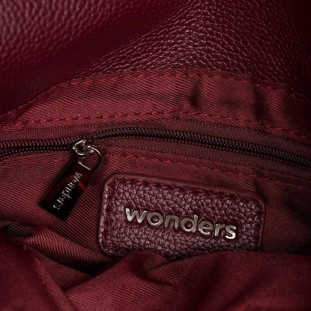 burgundy crossbody with 'wonders' branding on a light grey background