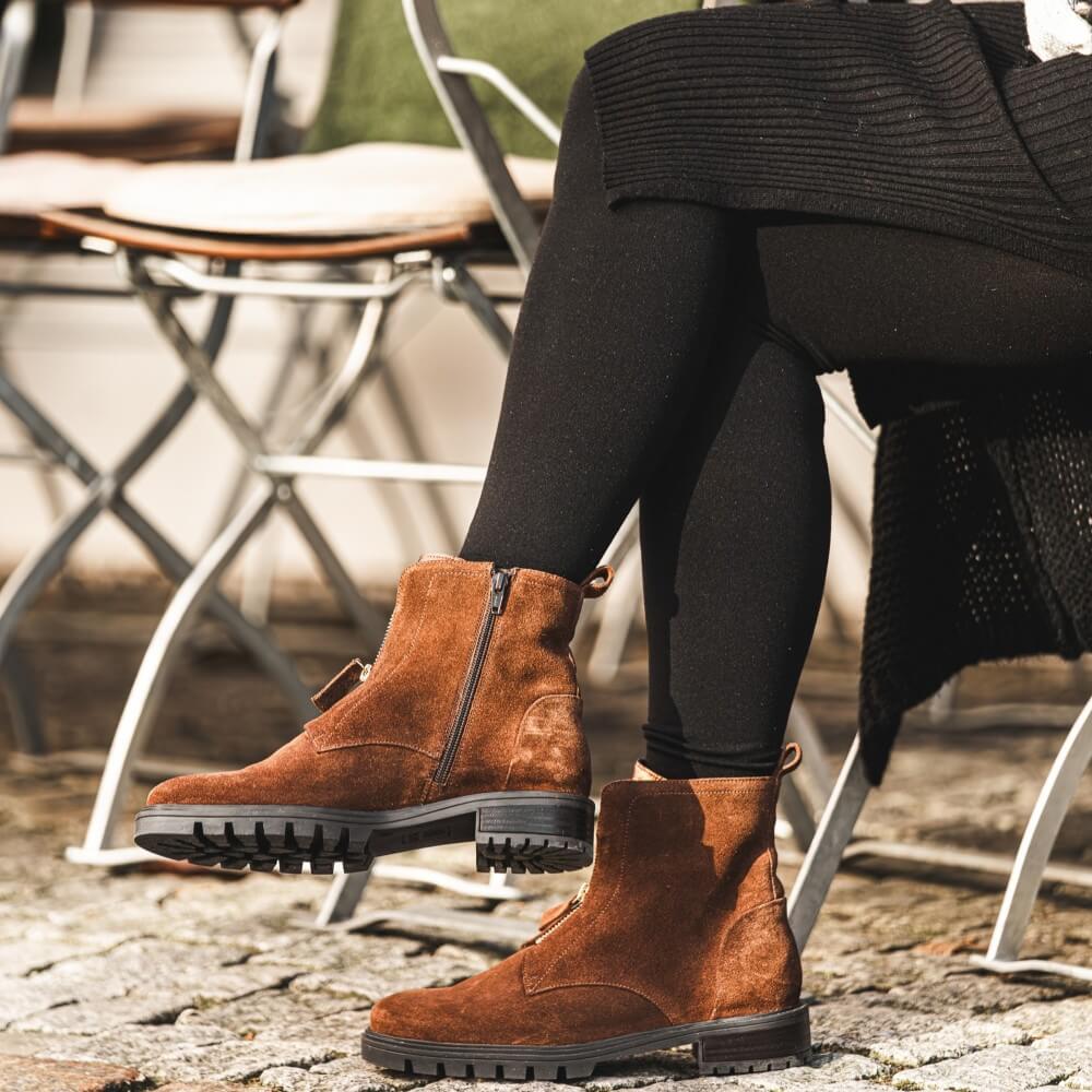 Brown suede boots worn by a person sitting outdoors on a stone surface.Ara Tulsa Suede Leather Ankle Boots 12-29520 Brown 