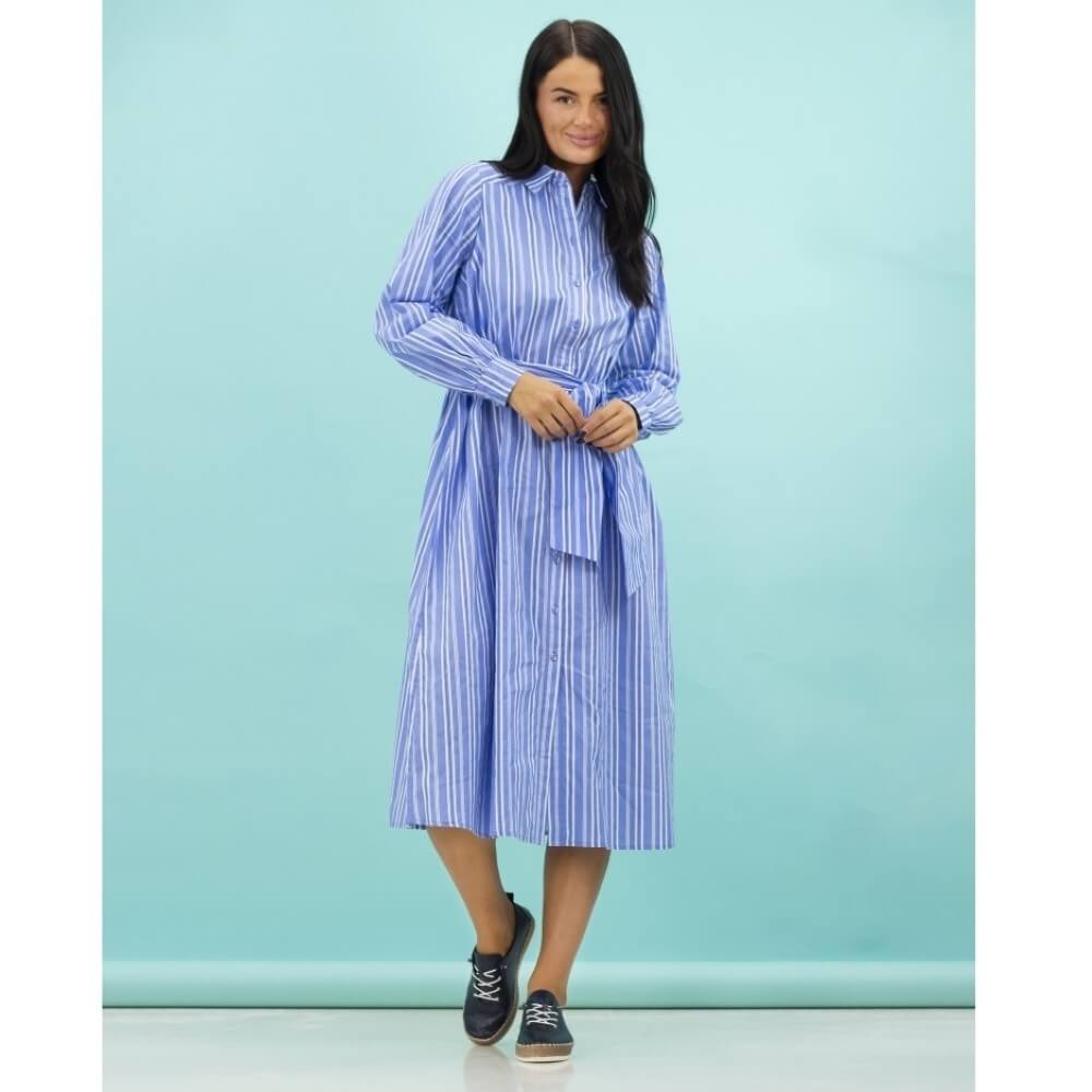 Woman wearing navy trainers and a blue striped dress against a light blue background