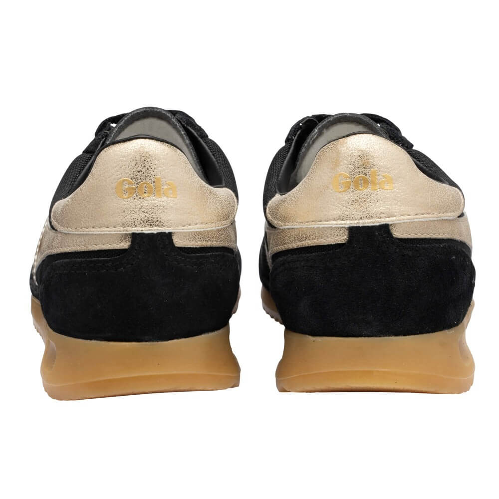 A pair of black and gold sneakers shown from the back, featuring a metallic gold heel tab with the brand name 'Gola' in gold lettering, a black suede heel section, and a tan rubber sole.