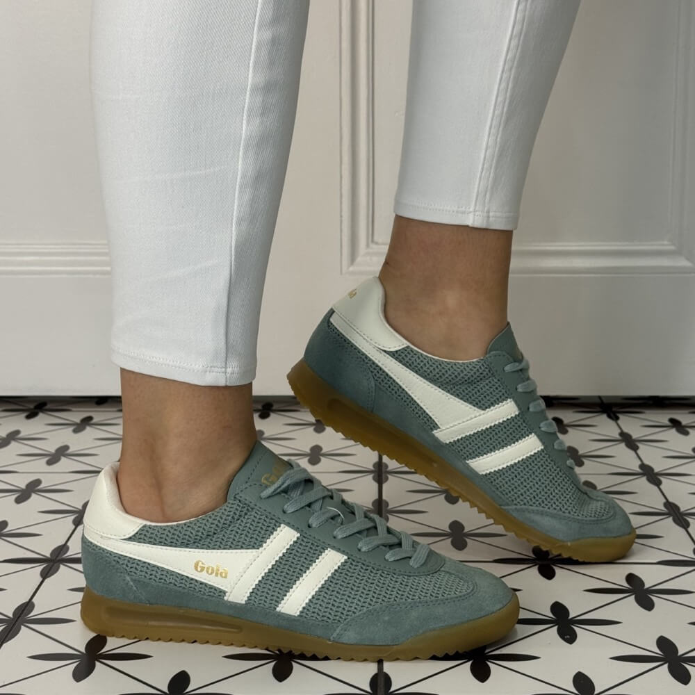 Gola Tornado Zephyr Green sneakers with white stripes worn indoors on a patterned floor.