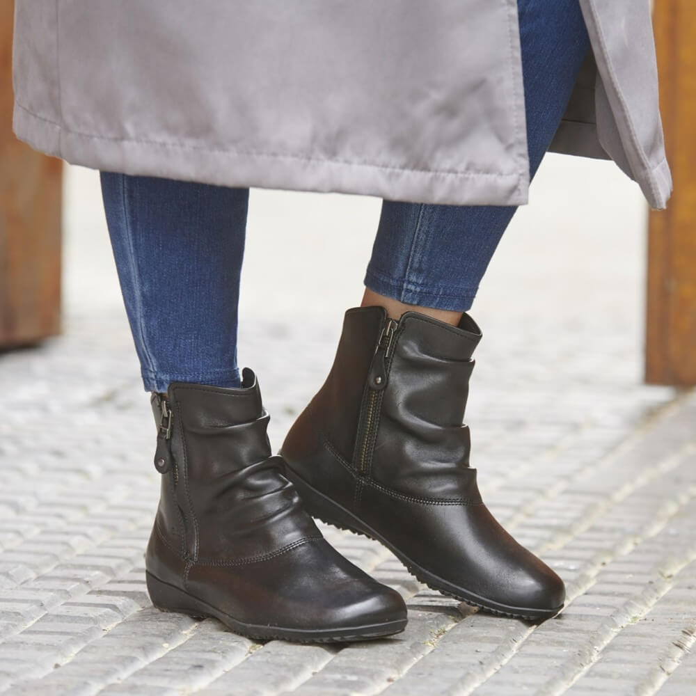 Person wearing black leather boots on a paved surface